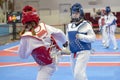 Two girls in blue and red Taekwondo equipment are fighting at doyang