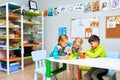 Russia, Moscow, 01.01.2019, two girls and a boy in kindergarten are sitting at a table and playing toys