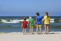 Two girls and two boys in colorful t-shirts standing back on a sandy beach Royalty Free Stock Photo