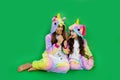 Two girls in bright costumes, eat lots candy canes on a green background Space for text. holiday concept