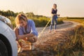 Two girls catch a tow rope on a broken car on a rural road in the rays of the sunset.