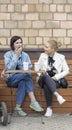 Two girls chat while sitting in a sidewalk cafe