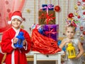 Two girls in Christmas costumes are with candlesticks from the bag with Christmas gifts