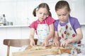 Two girls (5-6) cutting dough in kitchen