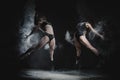 Two girls dance with flour in studio on black background, lights behind them and people helped girls Royalty Free Stock Photo