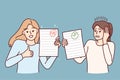 Two girls demonstrate paper with positive and negative mark for final test results