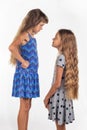 Two girls of different stature, one of them stood on a chair to be taller than the other Royalty Free Stock Photo