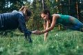 Two girls doing buddy workout outdoors performing push-ups to clap on grass