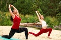 Two girls doing yoga and outdoor meditation, pair yoga classes, healthy lifestyle, meditation and wellness Royalty Free Stock Photo