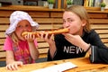 Two girls eat one big sandwich at at the same time. Childs divide one sandwich