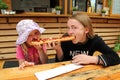 Two girls eat one big sandwich at at the same time. Childs divide one sandwich