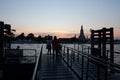 Two girls enjoy the sunset, standing on the banks of the river near the jetty of the river tram. Wat Arun is located on the river