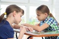 Two girls enthusiastically collect puzzles at the table at home