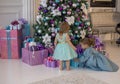 Two girls in fancy dresses are looking for Christmas gifts under a beautifully decorated tree. Royalty Free Stock Photo