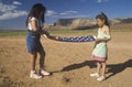 Two girls folding the American flag,