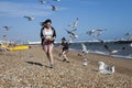 Two girls with food run away from gulls who attack them on the beach Royalty Free Stock Photo