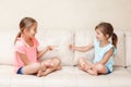 Two girls friends playing rock paper scissors hand game. Caucasian children sitting on a couch playing together. Interesting Royalty Free Stock Photo