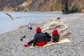 Two girls friends are resting on the beach of a seaside resort in identical jackets