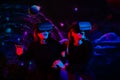 Two girls friends in virtual glasses are holding hands in the playroom in neon light