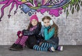 Two girls in front of the wall covered with graffiti Royalty Free Stock Photo
