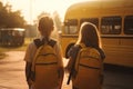 Two girls girlfriends go from school with backpacks to the school bus, rear view