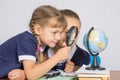 Two girls girlfriends looking at globe through a magnifying glass Royalty Free Stock Photo