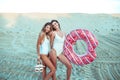 Two girls girlfriends standing sand with inflatable circle, beautiful women beach white bodysuit. Holidays sea on ocean Royalty Free Stock Photo