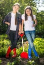 Two girls in gumboots posing with shovel on garden bed Royalty Free Stock Photo