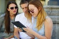 Two girls and the guy with interest look at the tablet screen. Royalty Free Stock Photo