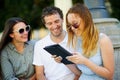 Two girls and the guy with interest look at the tablet screen. Royalty Free Stock Photo