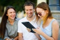 Two girls and the guy with interest look at the tablet screen. Royalty Free Stock Photo
