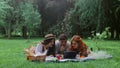 Two girls and a guy are lying on a picnic in the summer in nature and watching a movie on a tablet Royalty Free Stock Photo