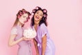 Two girls with hair curlers eating marshmellows. They are celebrating women`s day March 8. Royalty Free Stock Photo