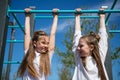Two girls hang on the horizontal bar on the playground