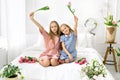 Two girls happily waving tulips sitting in bed. world children`s day