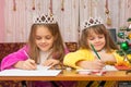 Two girls happily writing letter to Santa Claus sitting at a desk in the home environment