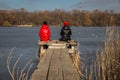 Two girls have a rest on a pier on the river bank Royalty Free Stock Photo