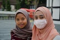 Two girls in hijab, one of them wearing a mask