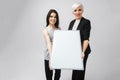 Two girls holding an empty poster isolated on white background Royalty Free Stock Photo