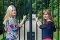 Two girls holding metal bars of entry gate Royalty Free Stock Photo