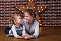 Two girls at home infront brick wall and decorative star Royalty Free Stock Photo