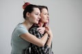 Two girls hug on a white background. Homosexual lesbian couple. Casual clothes.