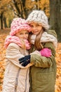 Two girls hugging in the park hats and scarves hand-knit rough Royalty Free Stock Photo