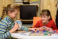 Two girls joyfully laugh while playing board games at the table Royalty Free Stock Photo
