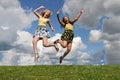 Two girls jumping in grass field Royalty Free Stock Photo