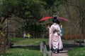 Two girls in kimono and with Japanese open umbrellas walk along the path of the Japanese garden during the cherry blossom