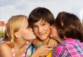 Two girls kiss boy in cheeks close up view Royalty Free Stock Photo