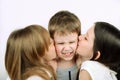 Two girls kissing little angry boy on the light background Royalty Free Stock Photo