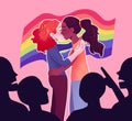 Two girls kissing with rainbow pride flag in the background being pointed at by homophobic crowd