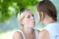 Two girls look at each other in the summer park